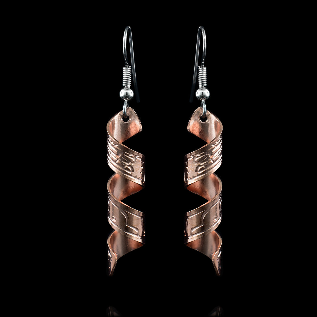 The earrings are made with a copper band that has been molded into a swirl. On the earrings is a hand-carved depiction on the Orca legend.