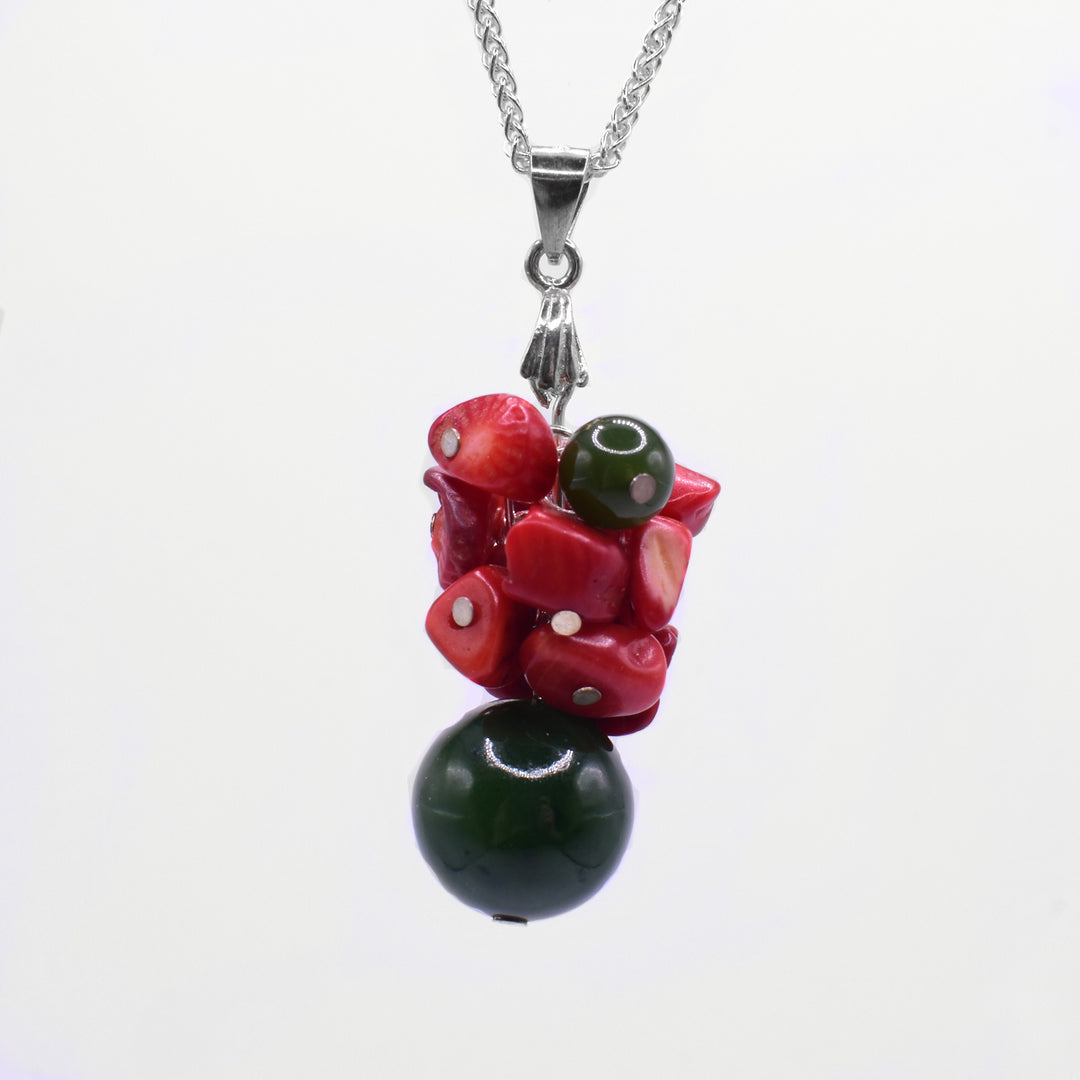 This red coral pendant features a large BC jade sphere at the bottom. Multiple small pieces of coral are gathered at the top, along with one small jade sphere. The pendant is linked together with a small bail.
