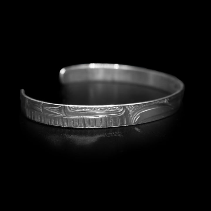 This dainty bracelet has a thin, sterling silver band with a gap in the back. There is a depiction of the Raven that has been beautifully carved into the surface of the band.