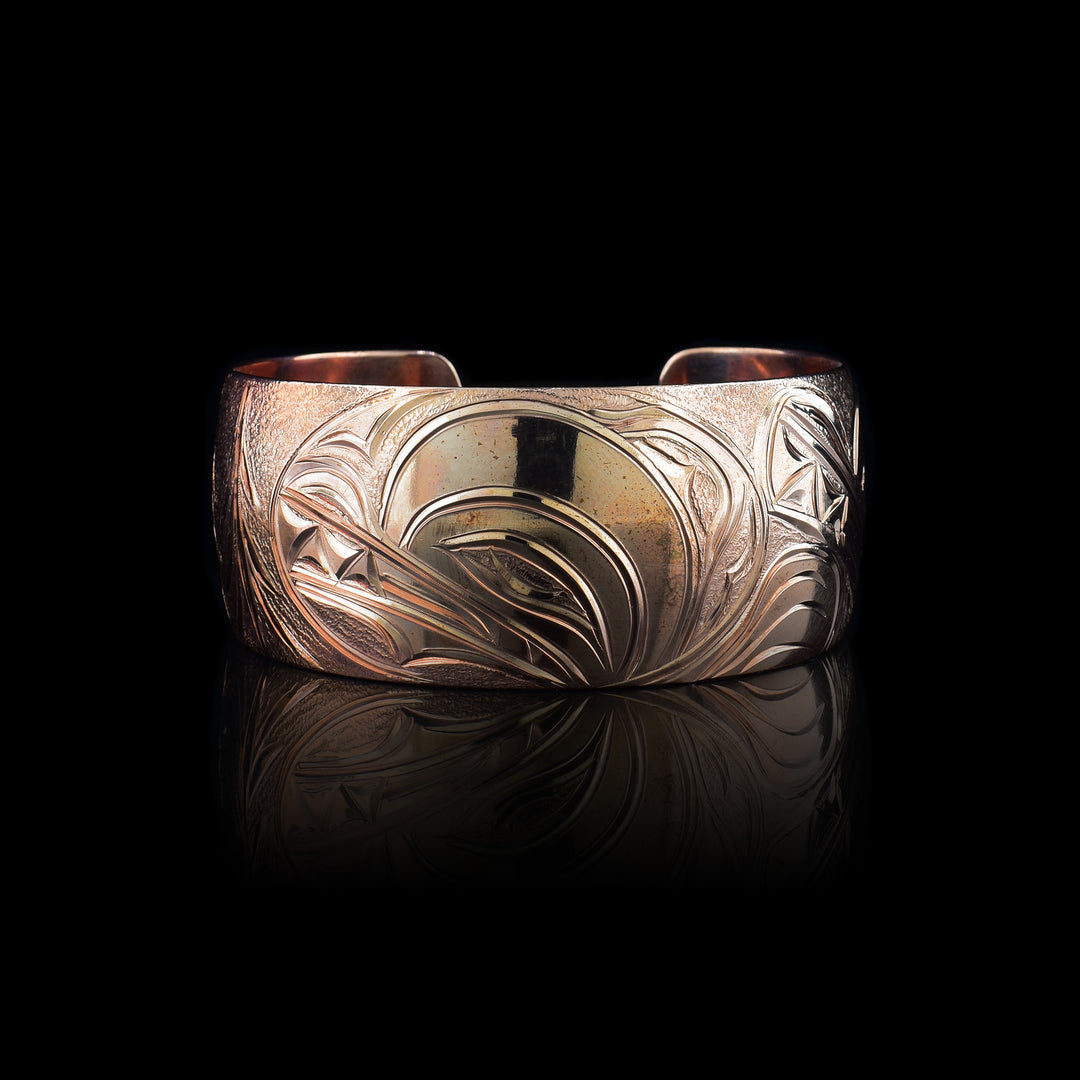 This stunning Wolf bracelet is made using copper and has a single, wide band with a gap in the back. I the center of the band, there is the head of the Baby Wolf placed in the middle of an oval design which represents the womb. On the right end of the band, the mother wolf is depicted with the side profile of her head which is tilted upwards. On the other end of the band there are simple pine trees carved into the band
