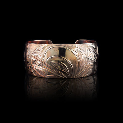 This stunning Wolf bracelet is made using copper and has a single, wide band with a gap in the back. I the center of the band, there is the head of the Baby Wolf placed in the middle of an oval design which represents the womb. On the right end of the band, the mother wolf is depicted with the side profile of her head which is tilted upwards. On the other end of the band there are simple pine trees carved into the band