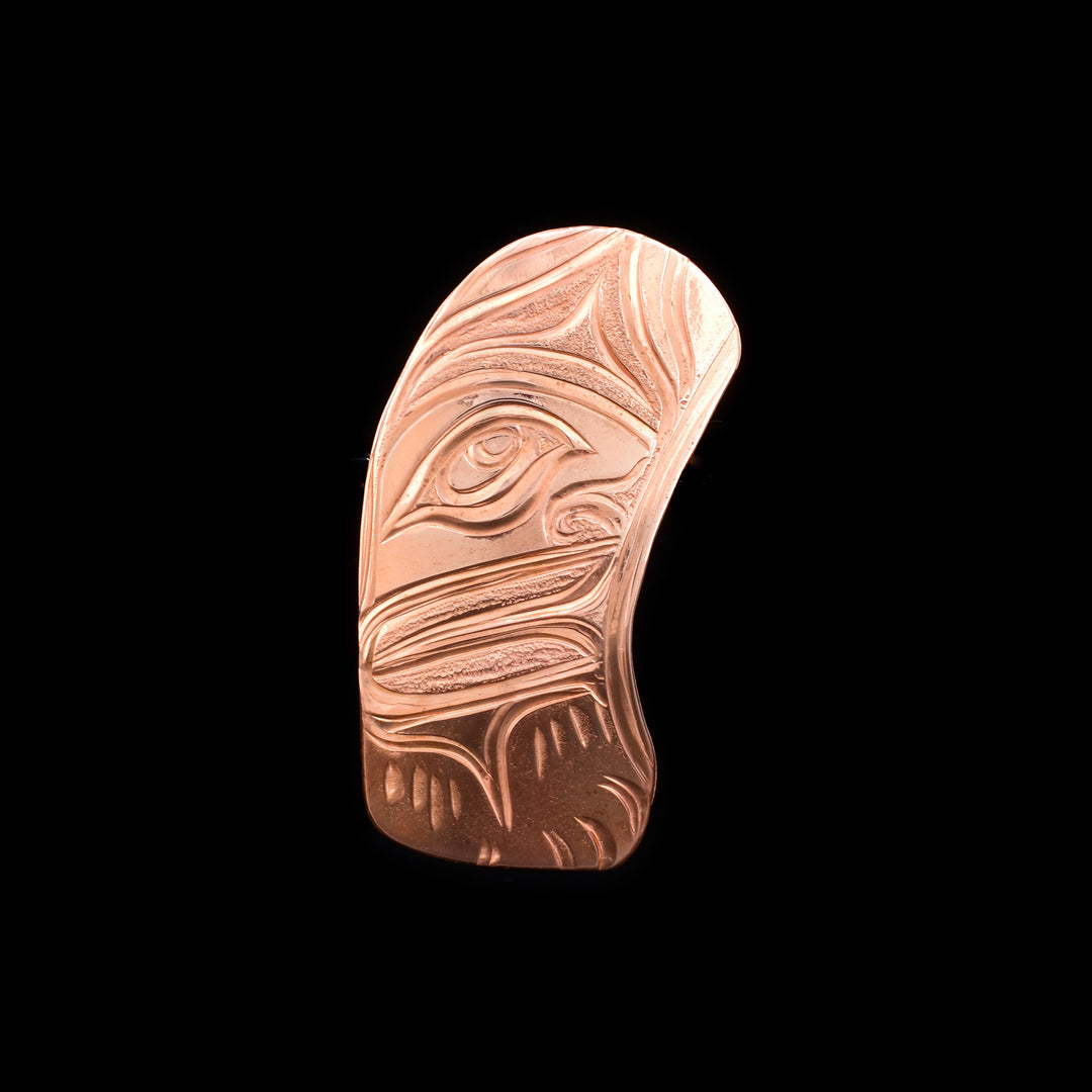 This Moon brooch pin is made from copper and has a round vertical design. There are carvings on the surface of the piece that depict the half Moon.