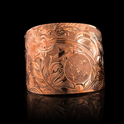 This large copper cuff bracelet has gorgeous carvings across the entire band depicting the Hummingbird, the Moon and floral designs. The band is very wide and tapered.