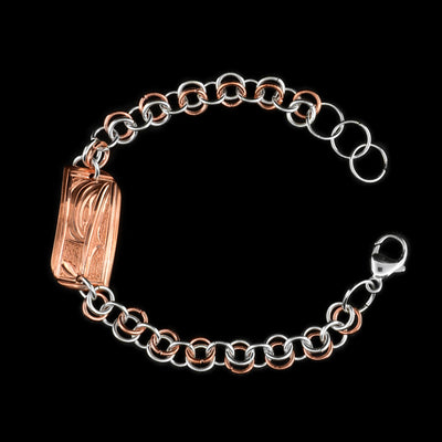 This silver and copper link bracelet is made from sterling silver and copper. This piece has a silver and copper chain with a rectangle charm at the top. There is a depiction of the Hummingbird carved into the surface of the copper charm.