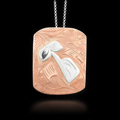 This large Hummingbird pendant is made from sterling silver and copper with a large, rectangular shape. There are carvings on the surface of the pendant that depict the Hummingbird and a flower. The Hummingbird is made using sterling silver and there are many designs around it.