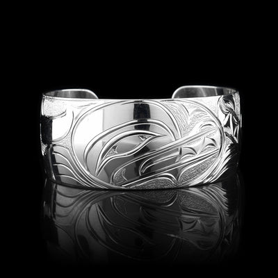This stunning Wolf bracelet is made using sterling silver and has a single, wide band with a gap in the back. There are intricate carvings on the surface of the piece that depicts the Baby Wolf in the womb and being watched over by its mother who is depicted in silver and carved on the side of the piece. On the other side of the band, the tail of the mother Wolf is depicted..