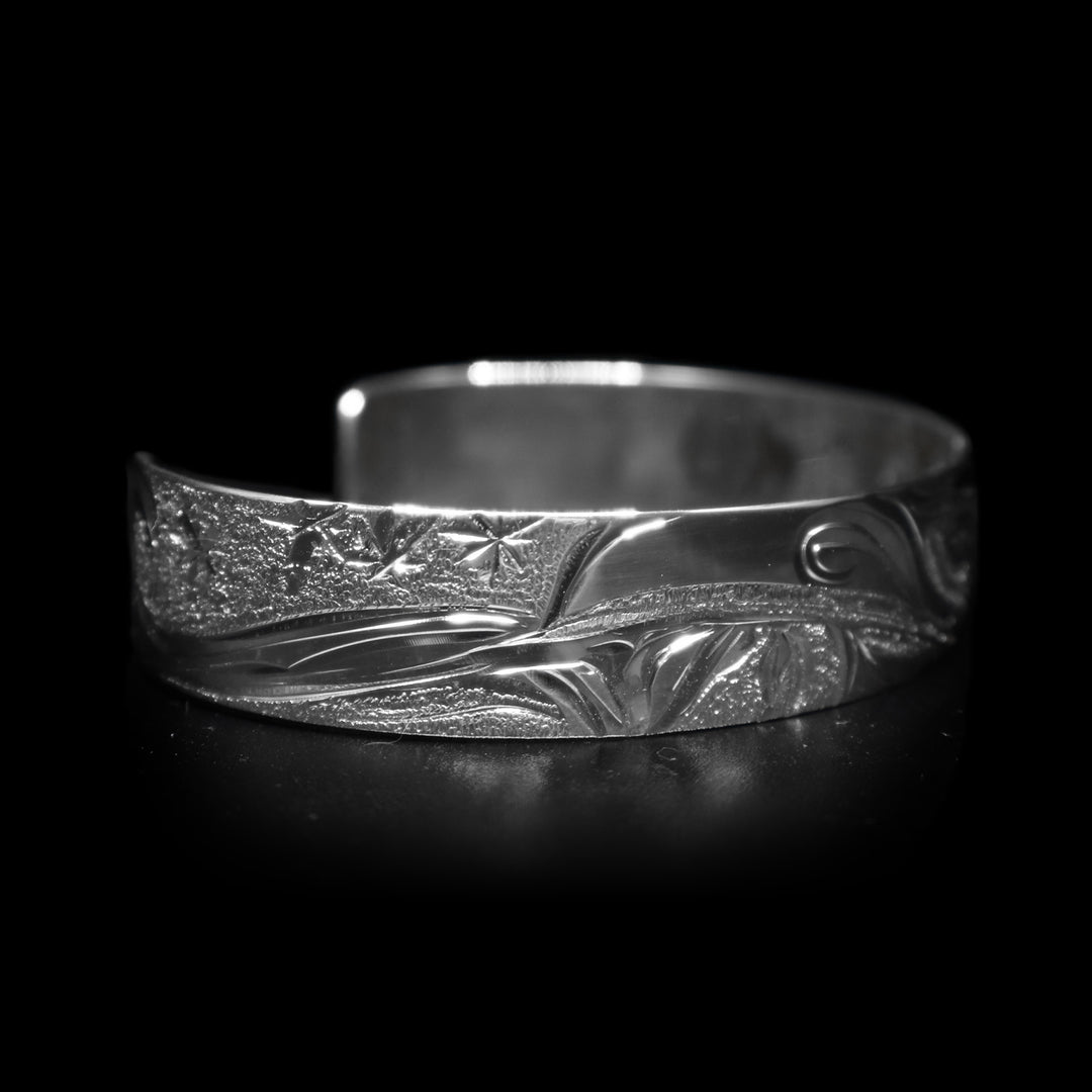 This dainty bracelet cuff has a thin, sterling silver band with a gap in the back. There is a depiction of the Raven in the night sky with the Moon legend and stars etched into the band. The head of the Raven is looking upward at the sky and extends around the majority of the band.
