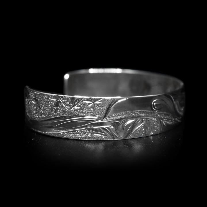 This dainty bracelet cuff has a thin, sterling silver band with a gap in the back. There is a depiction of the Raven in the night sky with the Moon legend and stars etched into the band. The head of the Raven is looking upward at the sky and extends around the majority of the band.