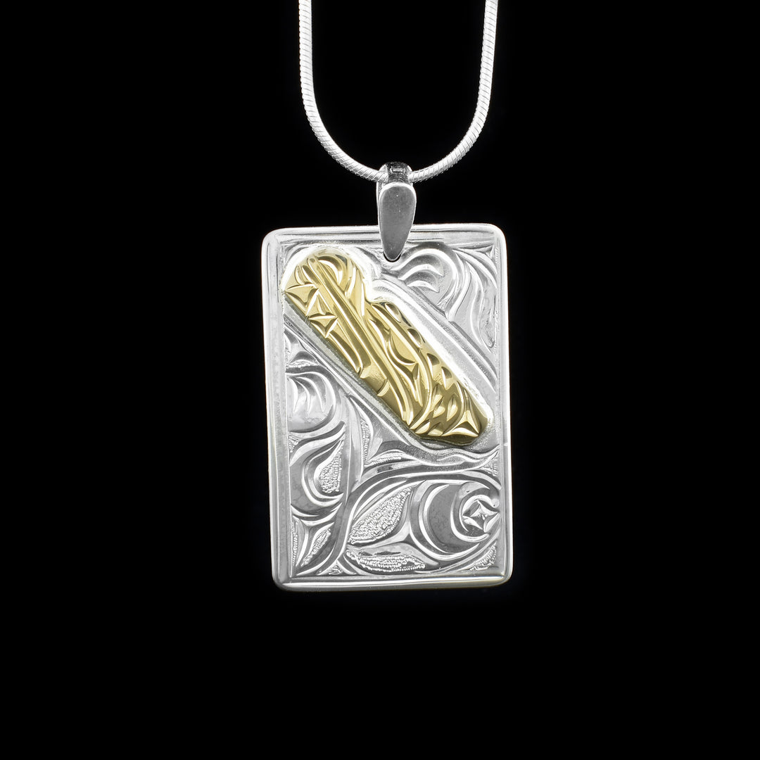 This gold Bear pendant is made from sterling silver, 14K gold and has a large, rectangular shape. There is a depiction of the Bear and designs carved into the surface of the piece and they head of the Bear is made from 14K gold.