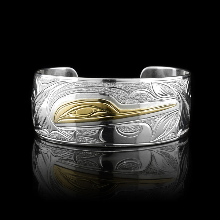This Hummingbird bracelet has been made with sterling silver and 14K gold with a single wide band and a gap in the back. There are carvings on the surface of the band depicting the Hummingbird. The head of the legend is made form gold.
