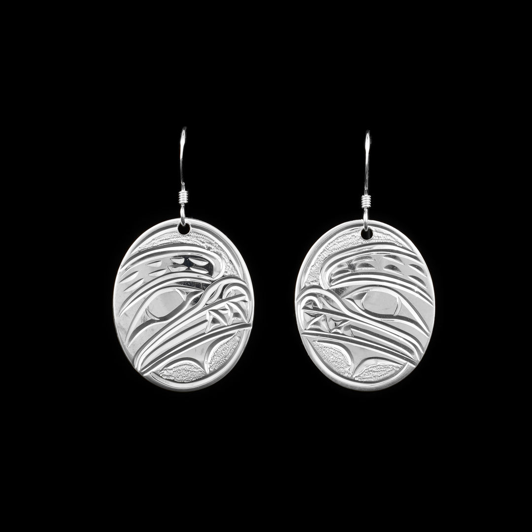 These dangling Bear earrings are made from sterling silver and have oval shaped hangs. There are depictions of the Bear carved into the surface of the hangs.