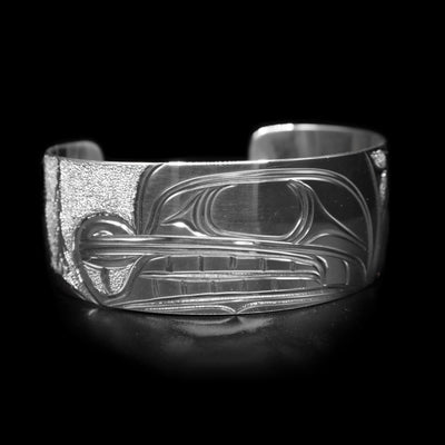 This sterling silver wide cuff bracelet has a depiction of the Beaver carved in the center of the piece and there are trees depicted in the background.