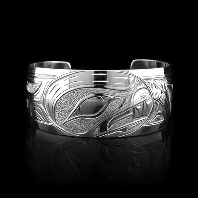 This stunning Bear bracelet is made using sterling silver and has a single, wide band with a gap in the back. There are intricate carvings on the surface of the piece that depicts the Baby Bear in the womb and being watched over by its mother who is depicted in silver and carved on the side of the piece. On the other side of the band, there are depictions the claws of the Bear.