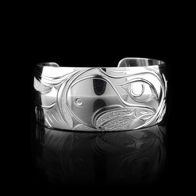 This Eagle bracelet cuff is made using sterling silver and has a single, wide band with a gap in the back. There is a depiction of the Baby Eagle in its egg being cradled by the wings of its mother that has been intricately carved into the surface of the band. There are textured dimple patterns made around this imagery.