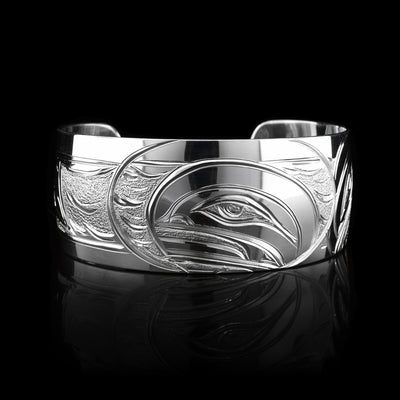 This stunning Orca bracelet is made using sterling silver and has a single, wide band with a gap in the back. There are intricate carvings on the surface of the piece that depicts the Baby Orca in the womb and being watched over by its mother who is carved on the side of the piece. On the other side of the band, there is a dorsal fin in the sea depicted.