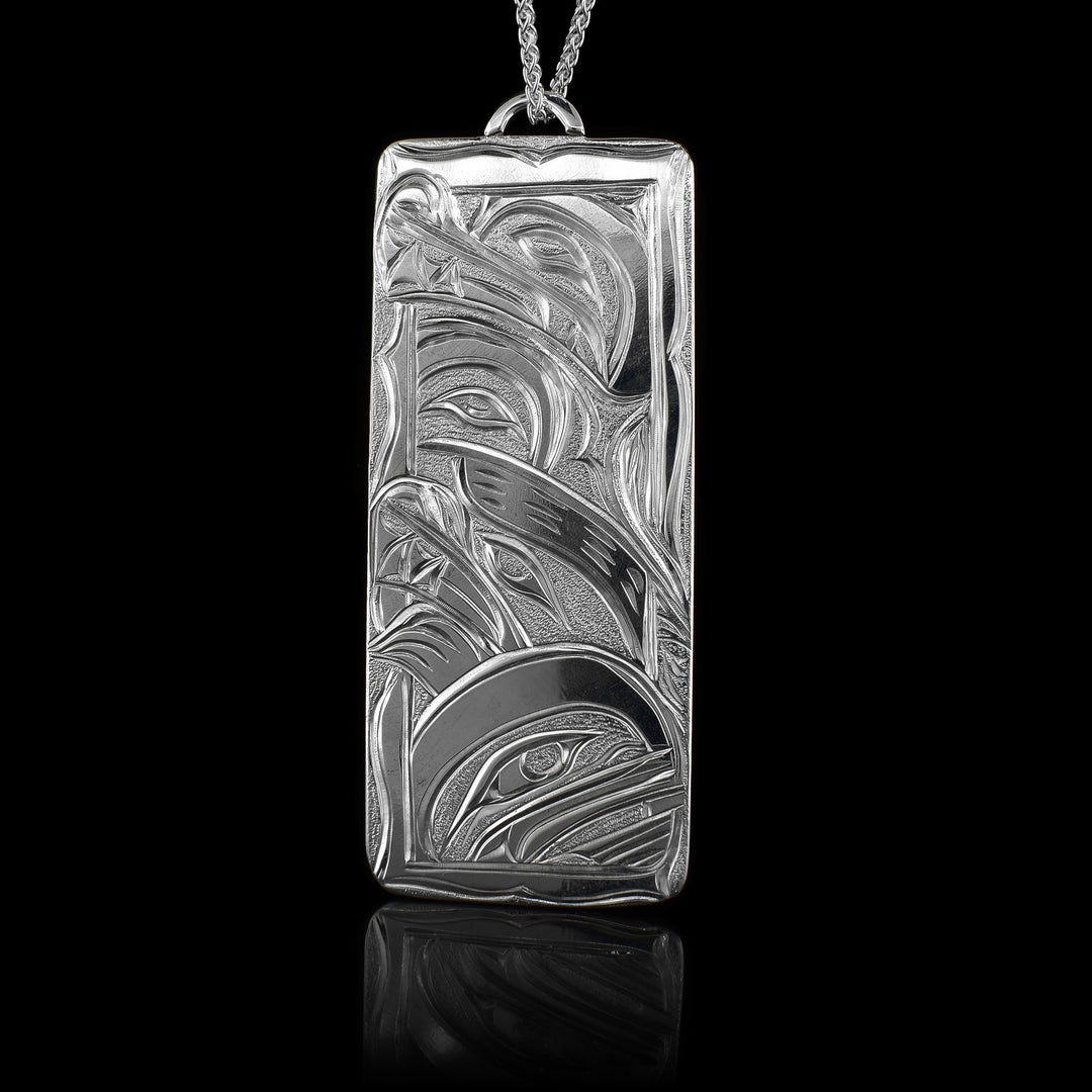This multiple Legends Wolf pendant is made form sterling silver and has a large rectangle shape. There are depictions of the Wolf, the Bear, the Hummingbird and the Orca carved into the surface of the piece.