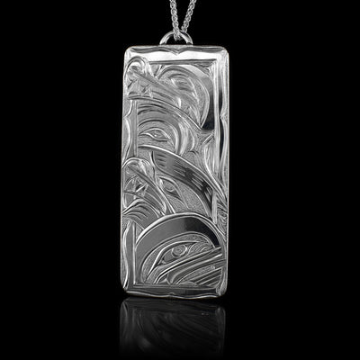 This multiple Legends Wolf pendant is made form sterling silver and has a large rectangle shape. There are depictions of the Wolf, the Bear, the Hummingbird and the Orca carved into the surface of the piece.