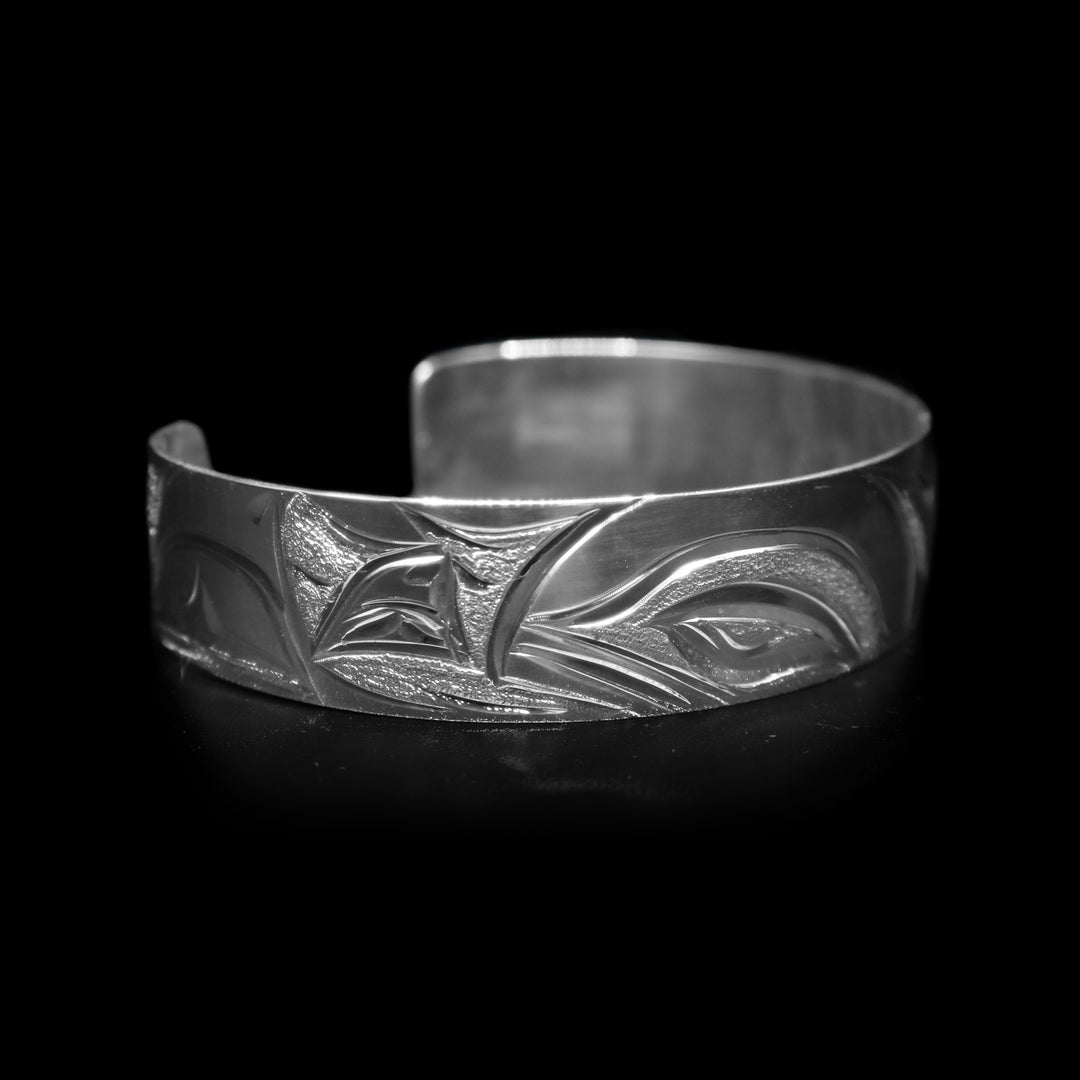 This Orca whale bracelet has a single, sterling silver band with a gap in the back. There are depictions of Orca whales beautifully carved into the surface if the band.