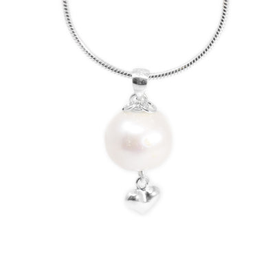 Round, white pearl pendant with small silver puff heart adornment hanging below. Two small, silver ring adornments hang off bail. Metal is sterling silver.