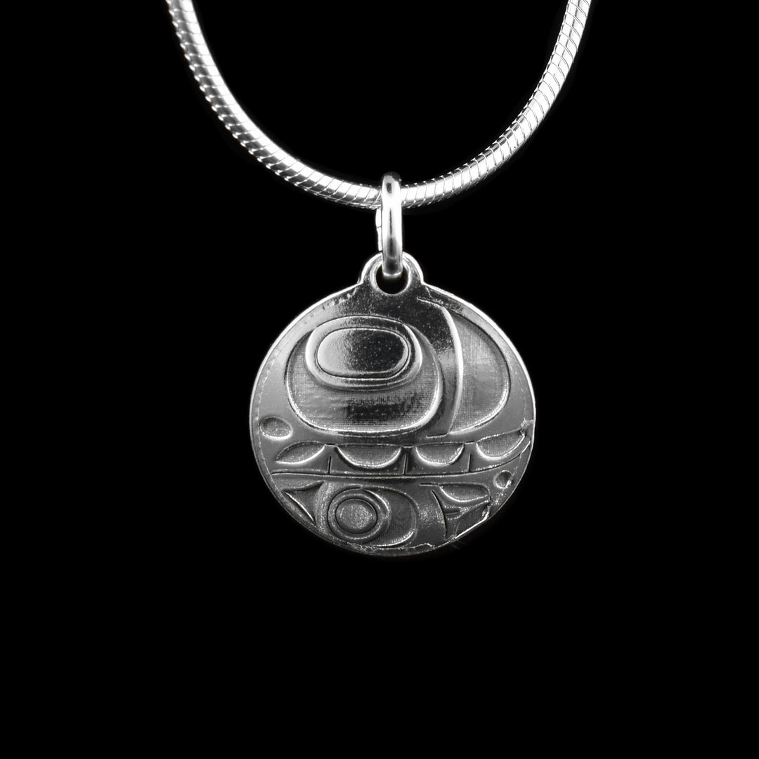 This dainty orca silver pendant features a circular design crafted from sterling silver. A side-profile depiction of the orca is cast into the pendant, with the top half showcasing the eye, mouth with visible teeth, and the distinct lower jaw.
