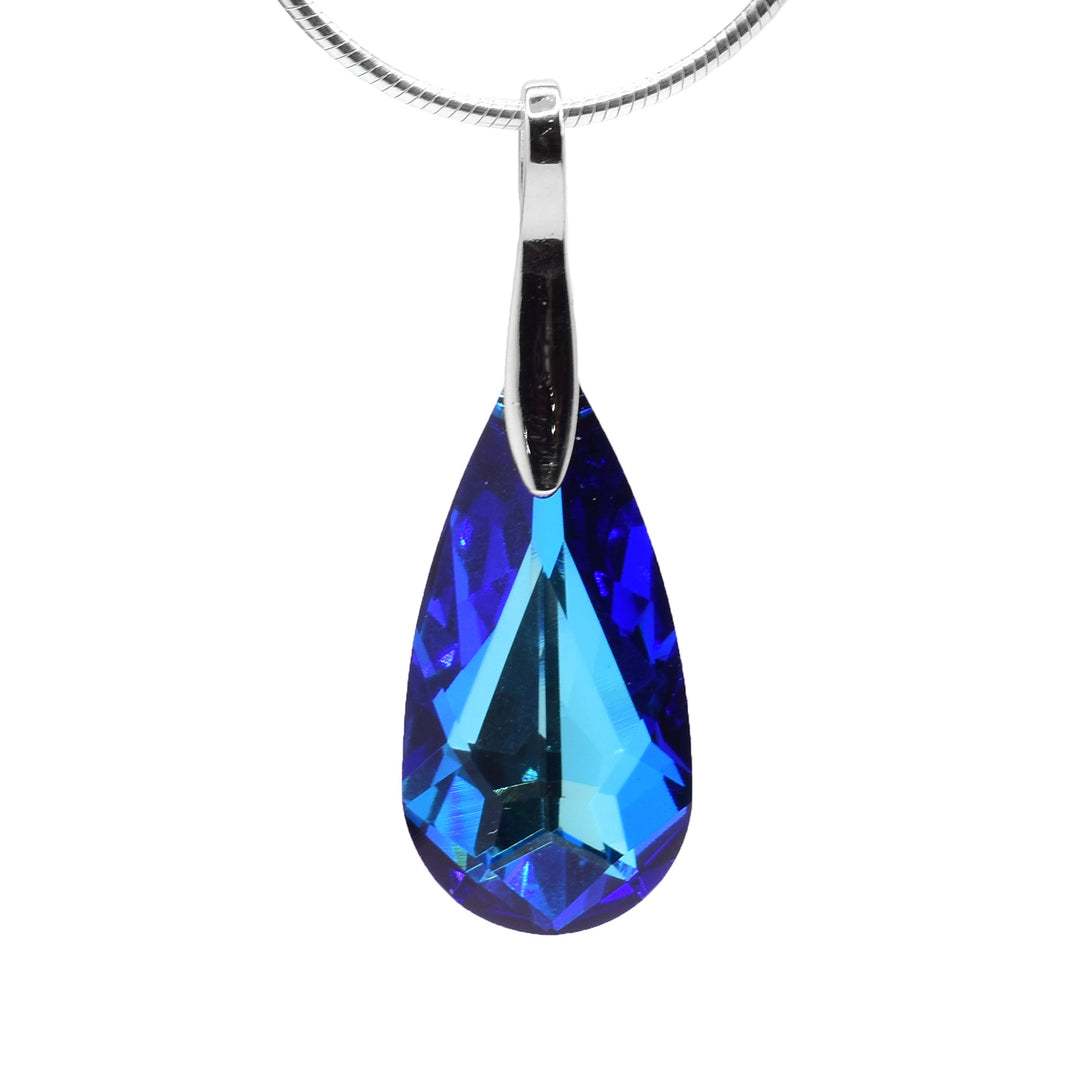 This teardrop crystal pendant has a teardrop shaped, Bermuda Blue Swarovski crystal that hangs down from a long, sterling silver bail. The pendant is a deep blue color and the bail has a solid designs and goes on top of the crystal.