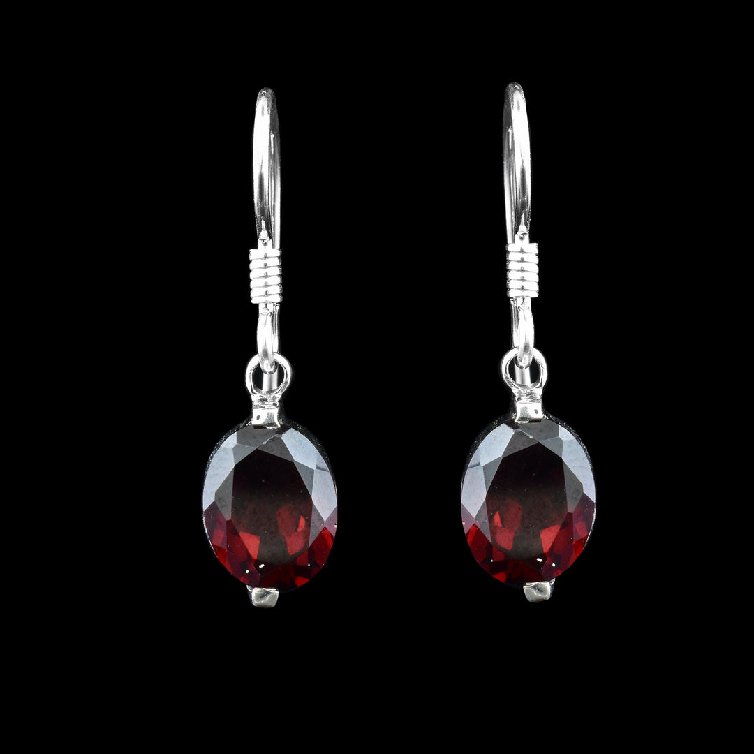 Deep red Garnet shaped in ovals hanging from sterling silver hooks create simple dangle earrings.