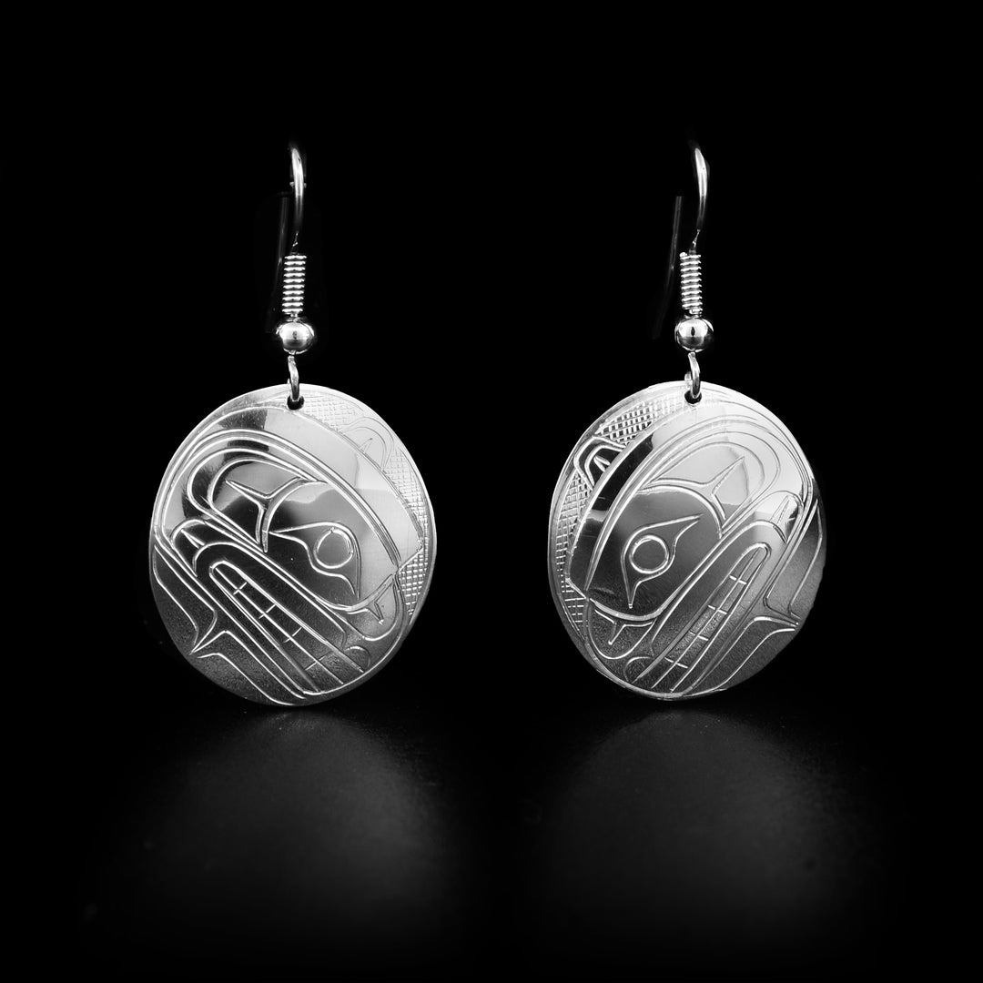 Domed, oval sterling silver dangle earrings with bear heads facing downwards. Cross-hatching background. Dangle earrings hand-carved by Coast Salish artist Travis Henry.
