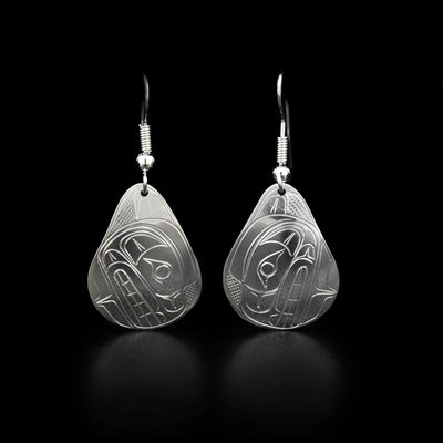 Each earring features a bear head facing downwards with a cross-hatching background. Sterling silver dangle earrings hand-carved by Coast Salish artist Travis Henry.