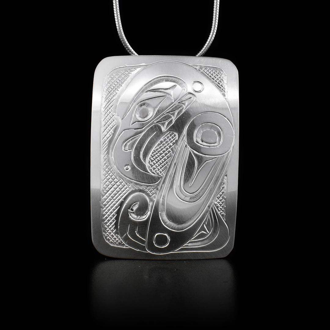 This sterling silver pendant is a large rectangle with carvings that depict the Raven on it