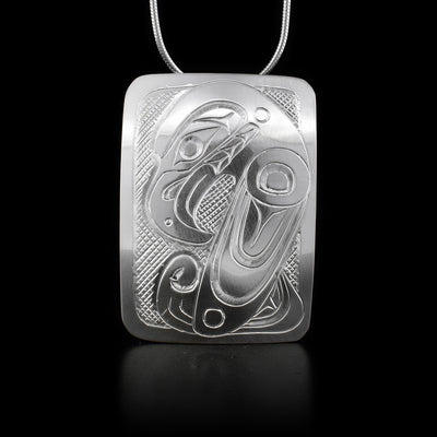 This stelring silver pendant is a large rectangle with carvings that depict the Raven on it