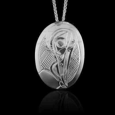 This Hummingbird pendant has been made form sterling silver and has a oval shaped. There is a depiction of the Hummingbird carved into the surface of the piece.