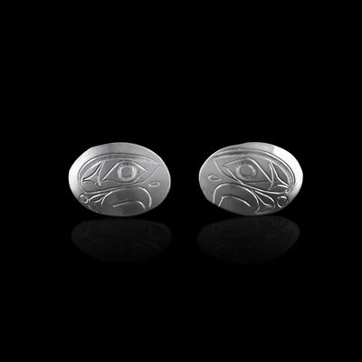 These Eagle stud earrings are made from sterling silver and have large, horizontal and oval shaped surfaces. There are depictions of the side profile of the head of the Eagle legend carved into the earrings.