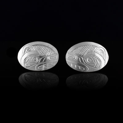 These Wolf stud earrings are made from sterling silver and have large, horizontal and oval shaped surfaces. There are depictions of the side profile of the head of the Wolf legend carved into the earrings.