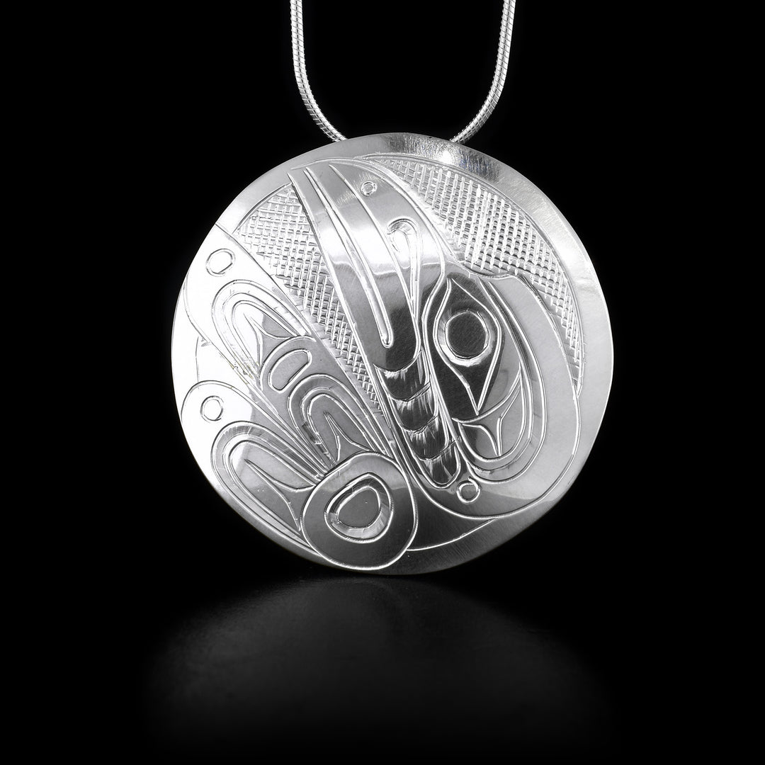 This sterling silver pendant is circle shaped and has carvings that depict the Raven on it.
