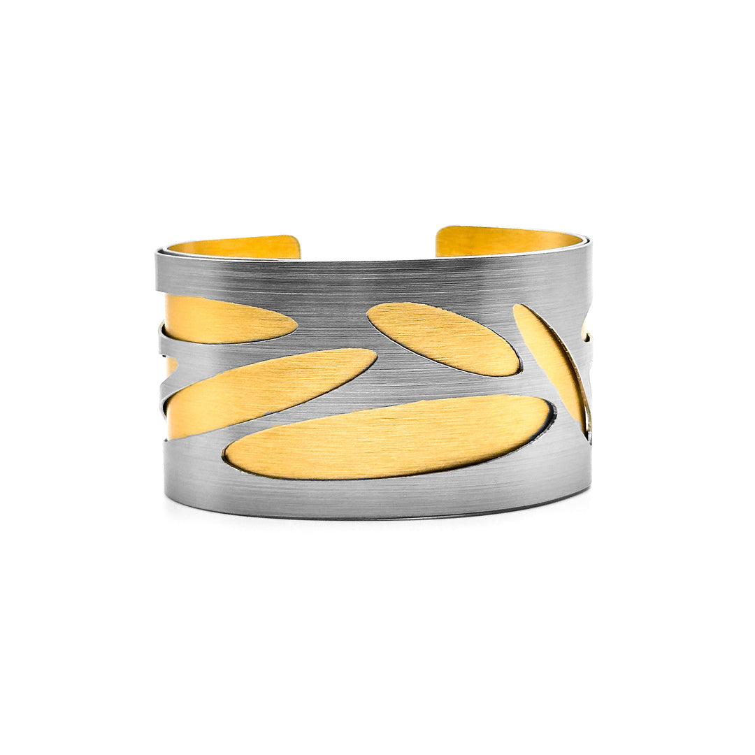 Anodized and brushed aluminum. Steel-coloured front layer has long ovals cut out, showing gold-coloured back layer.