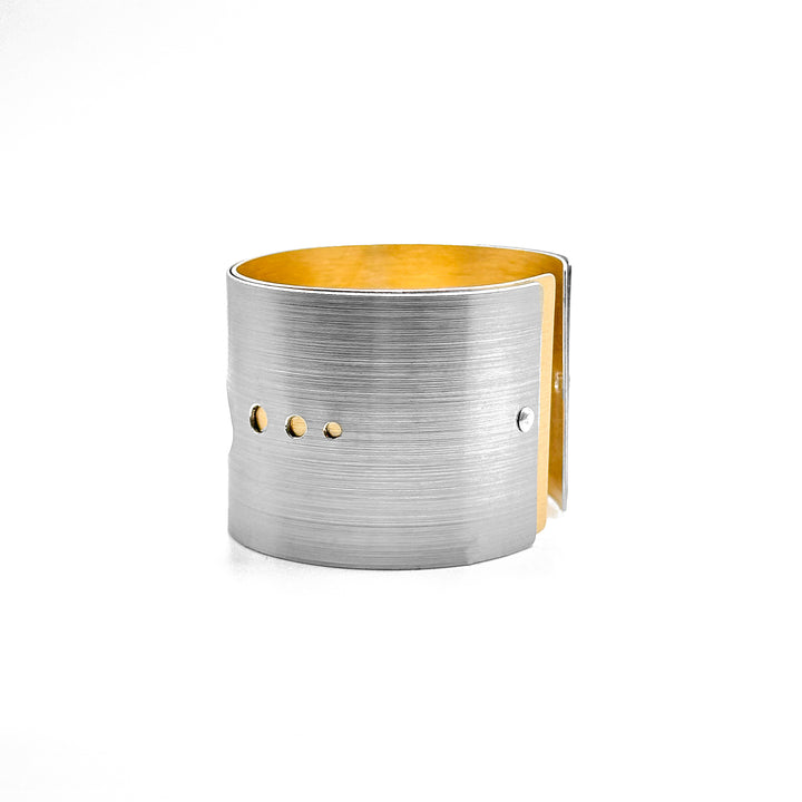 Side of bracelet with three cut out circles along middle-front part. Gold layer showing beneath. Sides are identical.