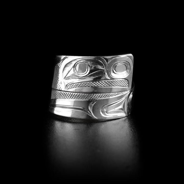 This sterling silver ring has a tapered band that wraps around the finger twice and is made from sterling silver. The head of the Eagle is shown at the widest point of the band at a side profile and its details have a slightly 3D appearance. There are cross hatching designs in the background of the scene.