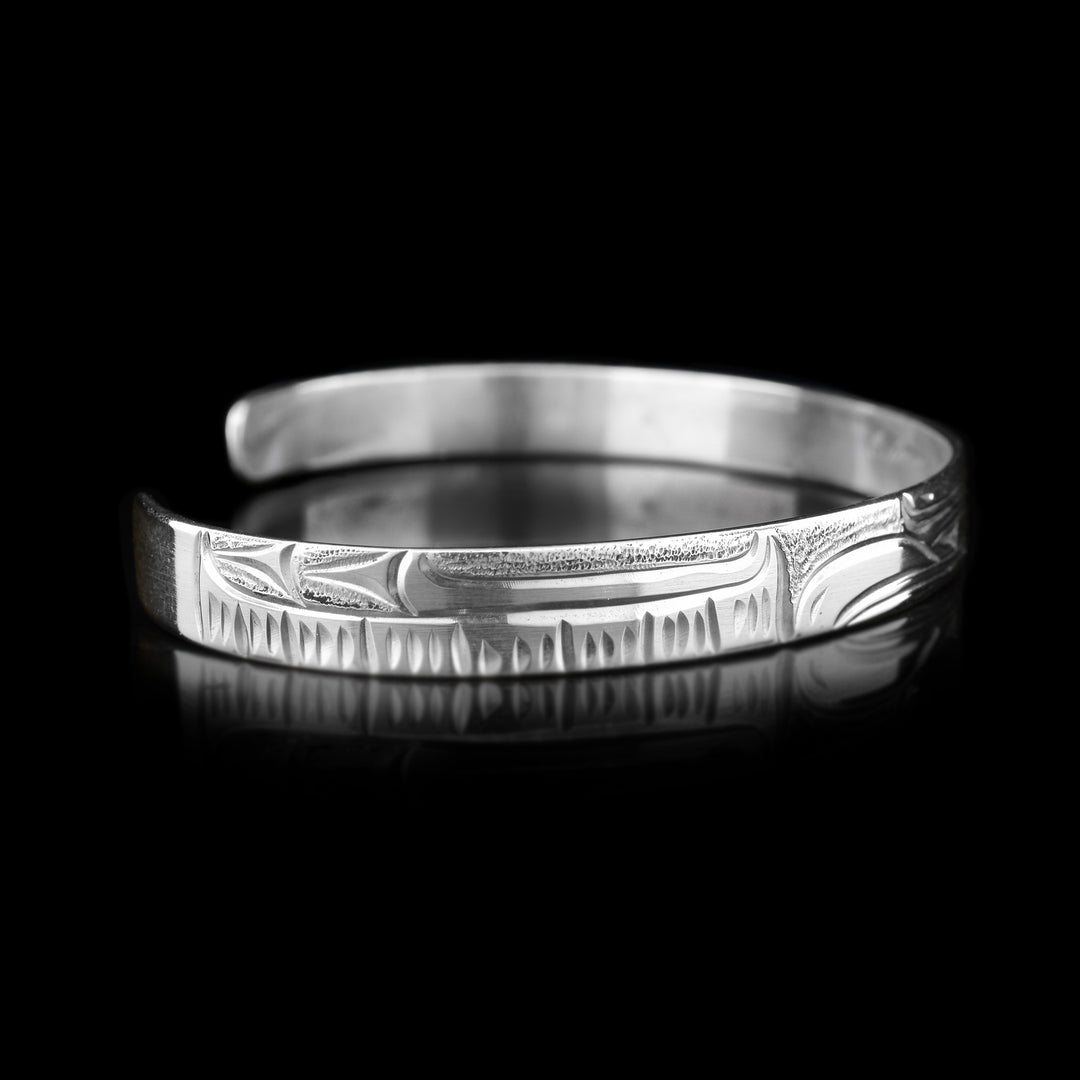 Left angle photo of the cuff bracelet depicts carvings representing the eagle's large, spread out wing and its feathers.