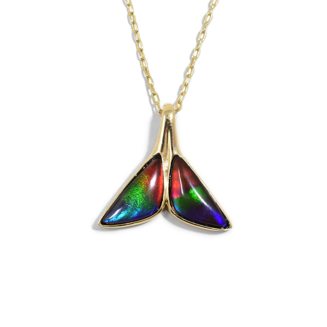 This funky whale tail pendant is made from 14K gold and ammolite gemstones. The pendant is made from gold and shaped like a whales tail with two ammolite gems on the fins.