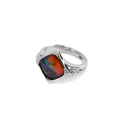 This ammolite ring is made from sterling silver, white topaz and ammolite gemstone. The ammolite is set in a diamond shaped signet and has white topaz gems set around it. The band is made from sterling silver and has designs around the signet and the topaz gems.