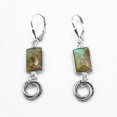 Long dangle earrings with lever-back hooks. Faceted rectangular labradorites hang above intertwined silver rings. Made of sterling silver and labradorite.