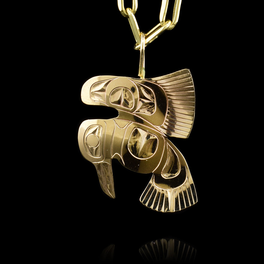 This 14K gold pendant is shaped like and has carvings on the surface of it that depict the Raven with its wings out.