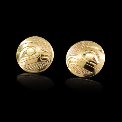 These 14K gold stud earrings have large circular surfaces with depictions of the Thunderbird carved into them.