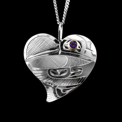 This sterling silver heart pendant necklace is large and has a beautiful heart shape. There is a depiction of the Hummingbird that is beautifully carved into the surface of it and there is an amethyst held in 14K gold in the eye of the Hummingbird.