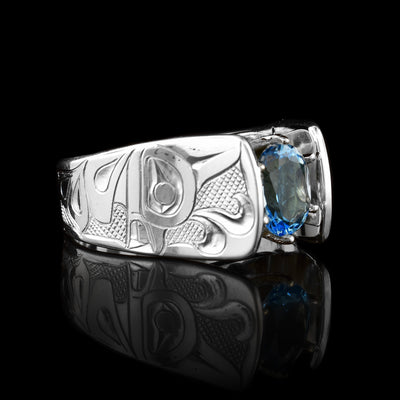 This Orca ring has a wide and tapered band that extends in cathedral style above the blue topaz gem that is set in 14K gold claws. There are carvings made on the band that depict the Orca.