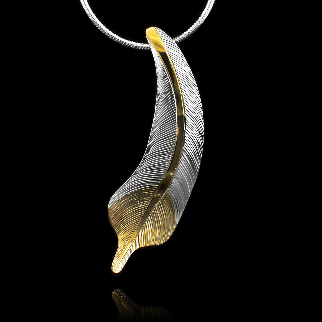 This gorgeous feather pendant is made from sterling silver and 18K gold plating. The pendant is feather shaped and have intricate carvings on the surface of it to make it look like a feather. There are gold highlights in the center of the feather and at the bottom of the piece.