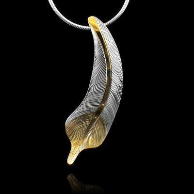 This gorgeous feather pendant is made from sterling silver and 18K gold plating. The pendant is feather shaped and have intricate carvings on the surface of it to make it look like a feather. There are gold highlights in the center of the feather and at the bottom of the piece.