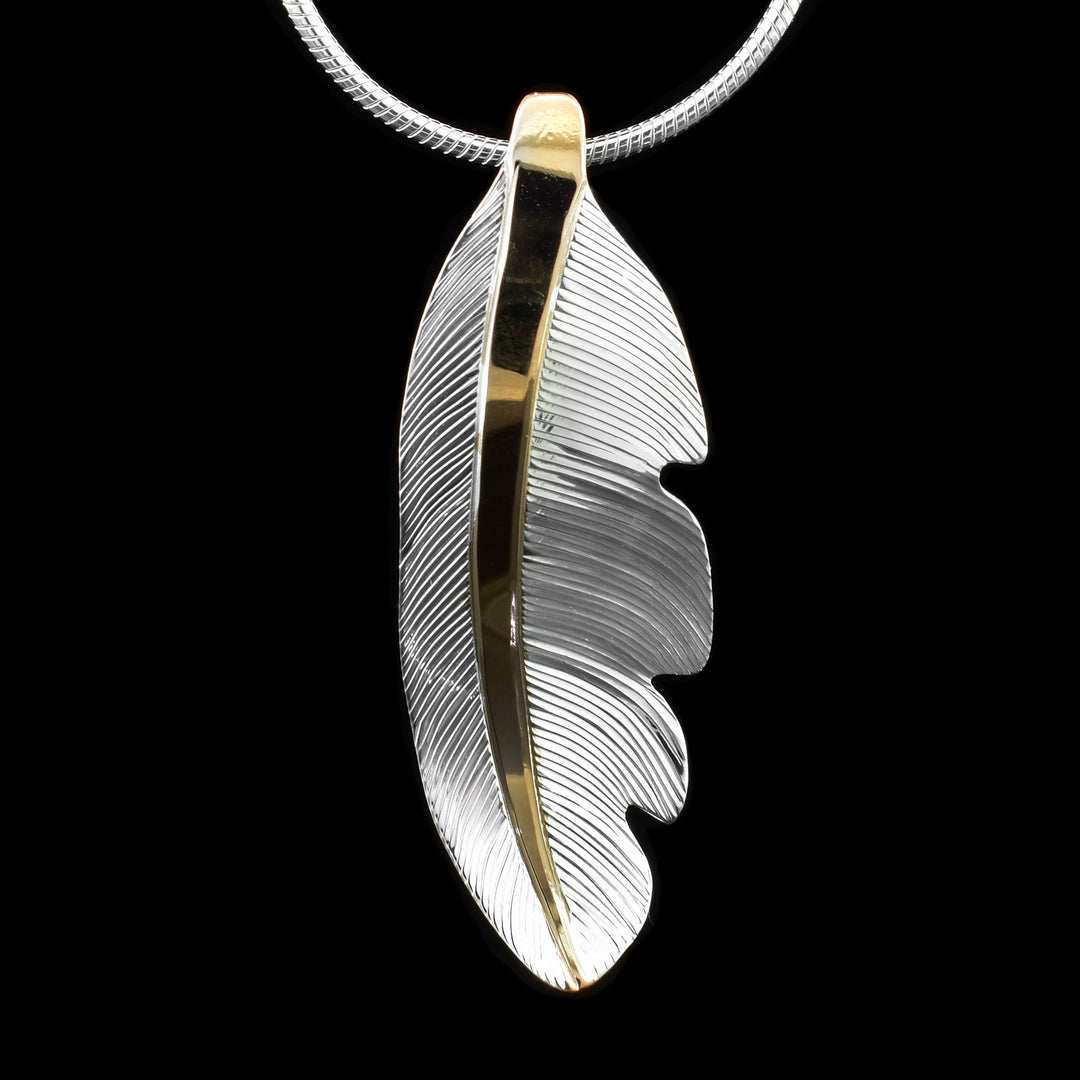 This gorgeous feather pendant is made from sterling silver and 18K gold plating. The pendant is feather shaped and have intricate carvings on the surface of it to make it look like a feather. There are gold highlights in the center of the feather.