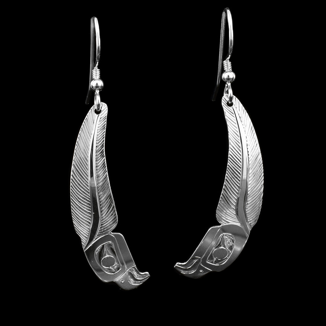 These sterling silver feather earrings are long and have depiction of the head of the Eagle carved into the bottom of them. The rest of the hangs are curved slightly and have carvings depicting a large feather.