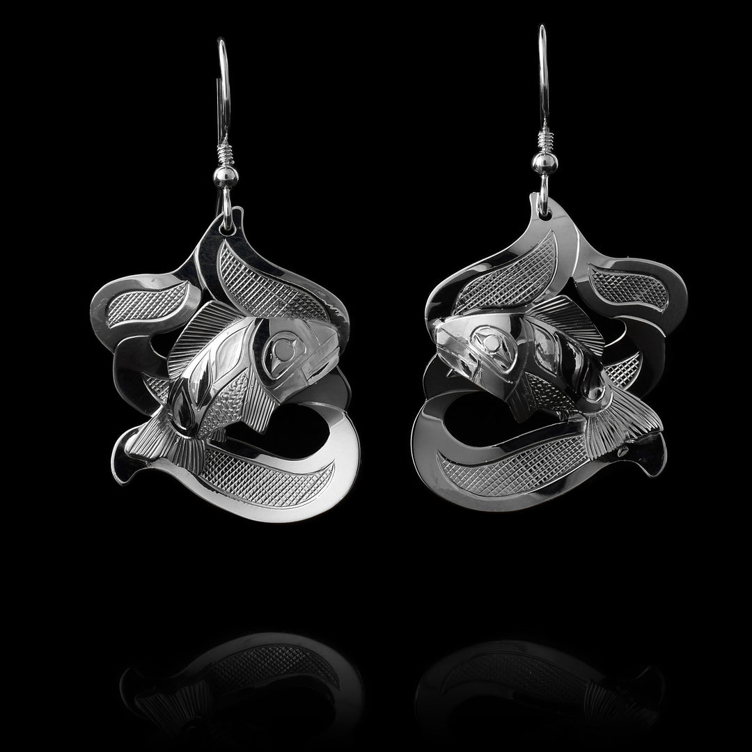 The Salmon earrings are made using sterling silver and have abstract hangs depicting the Salmon legend in ocean waves. The waves are made with cutout pieces and the salmon is set in the front of then. There are carvings made on the piece depicting the scene.